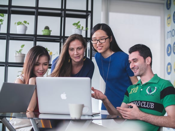 4 employees looking at a laptop in a modern office