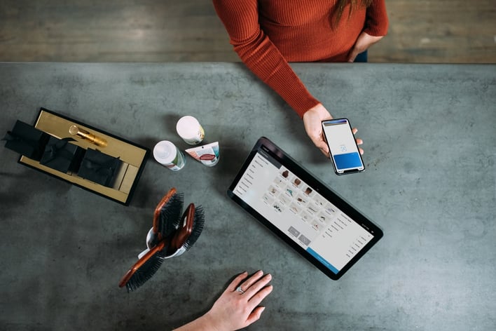two people at desk with phone, monitor and grooming products
