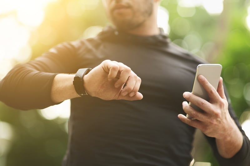 Man using wearable fitness tracker and smartphone