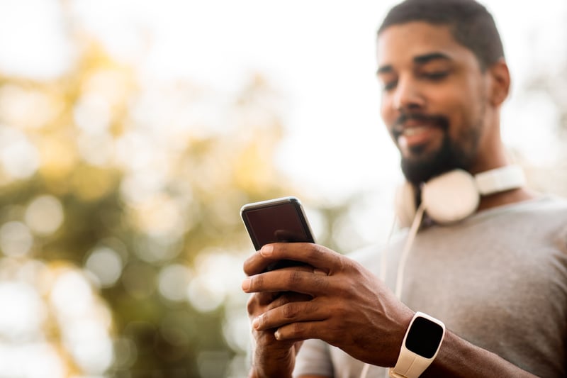 Young man chatting online on his smart phone outdoors