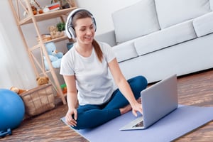 Women on yoga mat with headphone and laptop