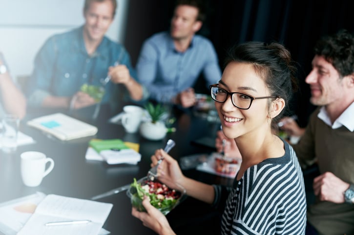 Co-workers around conference table eating salad