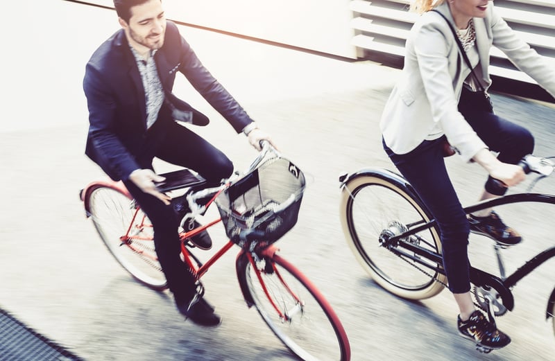 man and woman cycling in business attire