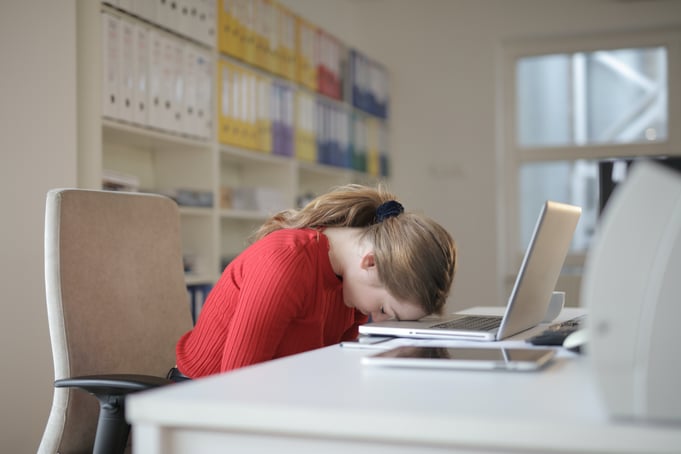 Female office worker with head on laptop