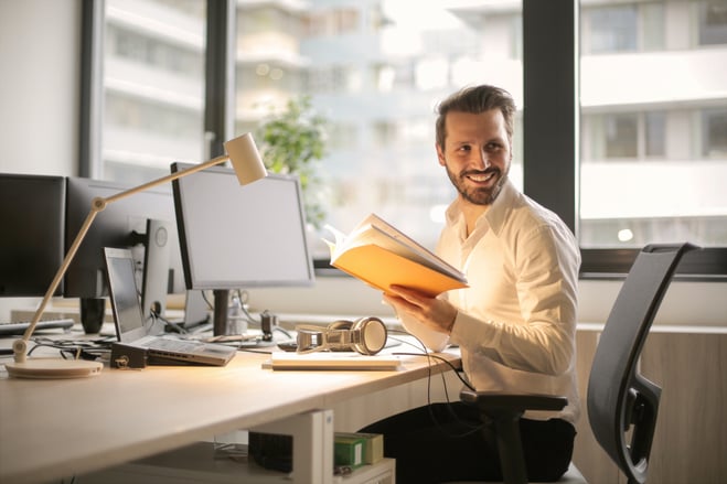 Man at desk holding a book
