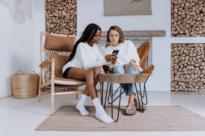 Two young seated women looking at a cell phone together