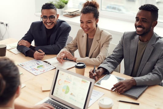 Smiling employees at conference table with laptops