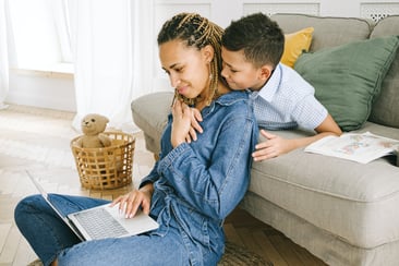 Boy hugging mom on laptop