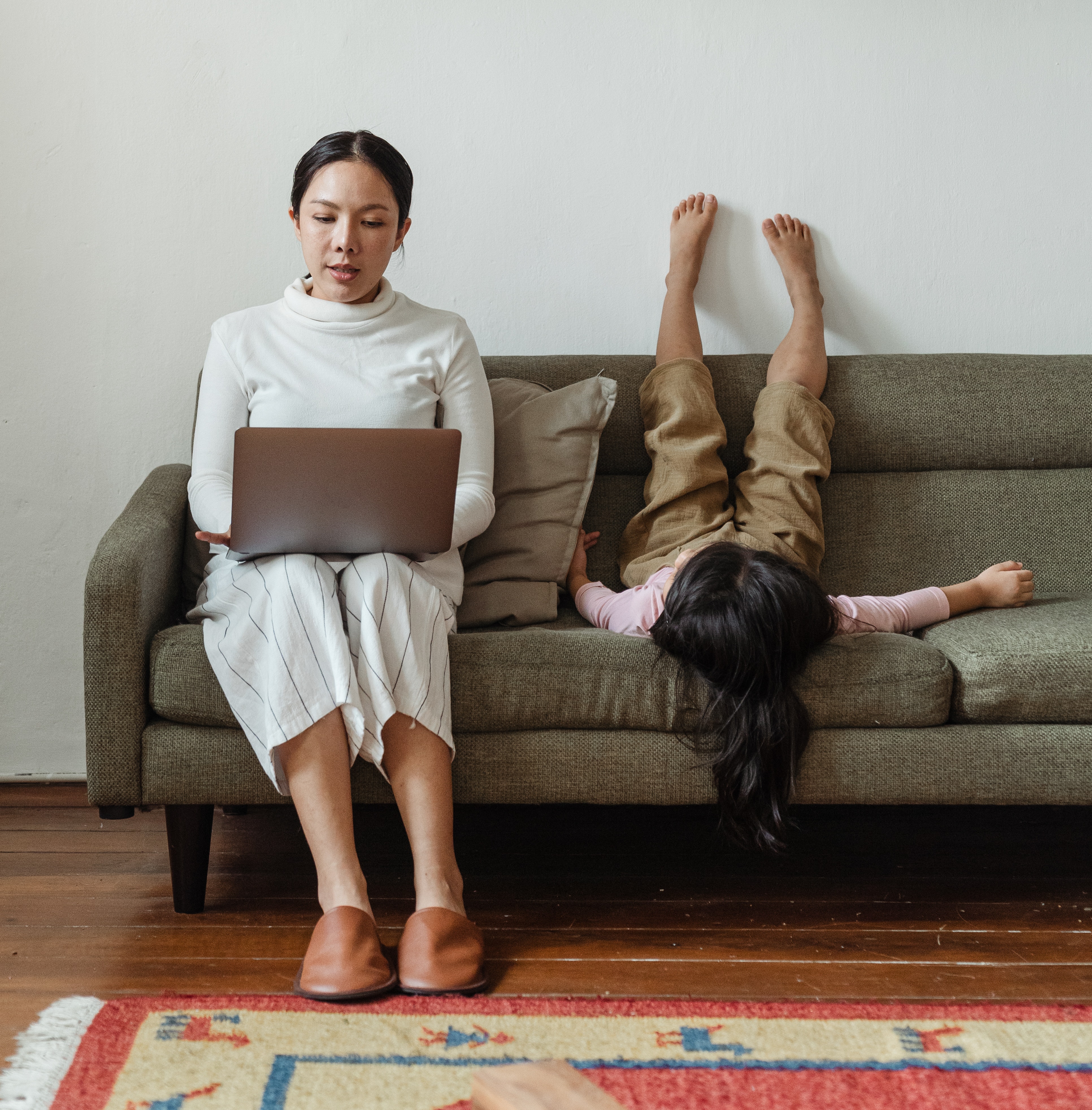 Woman with laptop sitting on couch with child