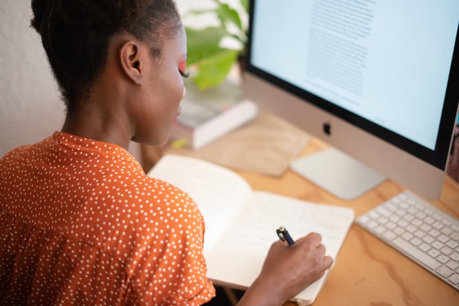 Woman at desk writing in notebook