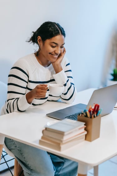 Smiling woman with tea cup at laptop