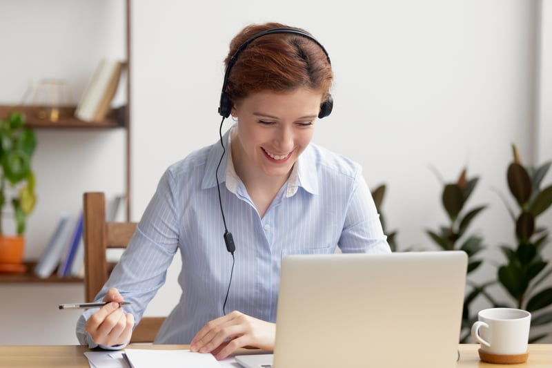 smiling woman on headphones at laptop