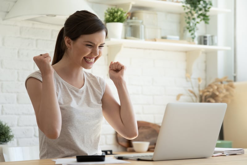 woman celebrating in front of laptop