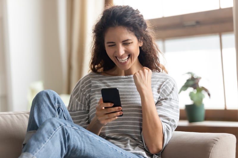 woman celebrating while holding smartphone