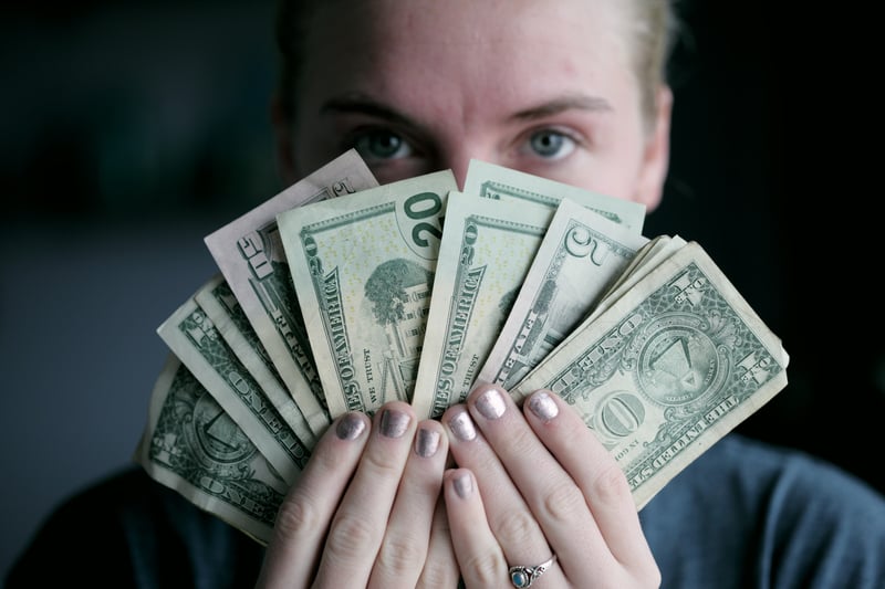 woman holding american money in front of face