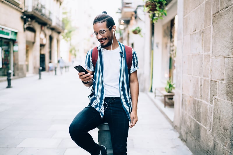young black man smiling while using smartphone