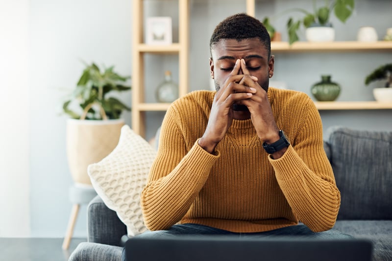 young black man stressed out sitting on couch