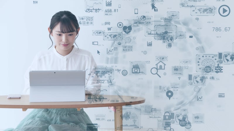 young woman using laptop with technology icons floating in foreground